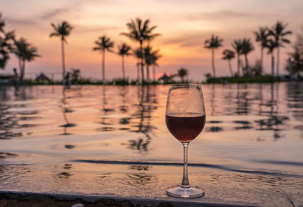 Romantic sunset by the pool with a glass of red wine