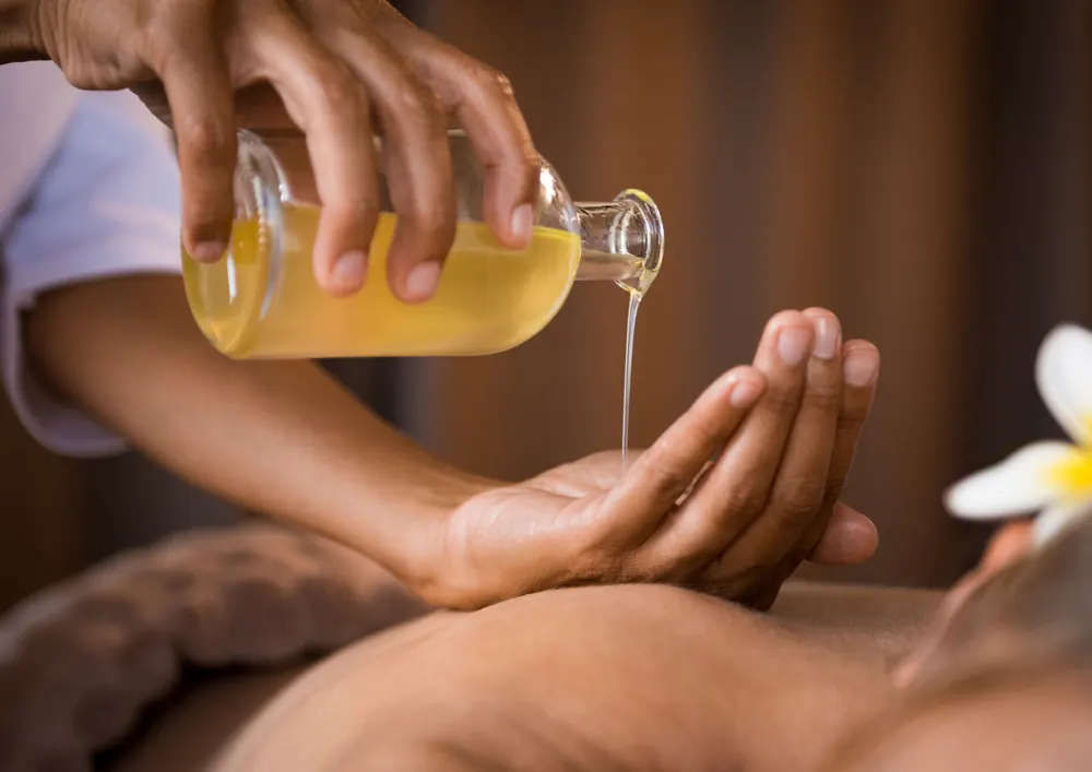Spa oil being poured into hands before a massage treatment