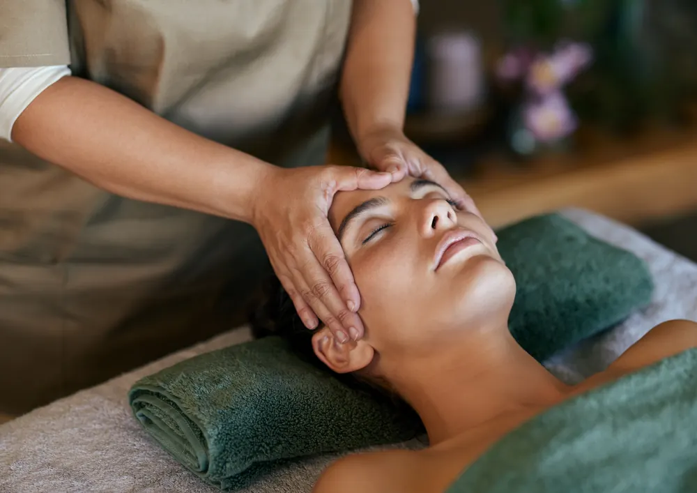 Relaxing facial massage treatment with soft towels and spa greenery